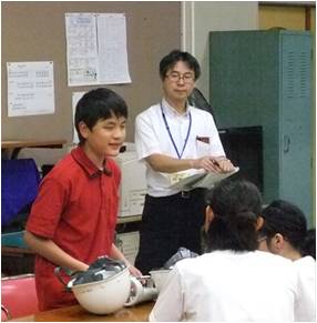 避難訓練が終わり反省会。反省を立って発表する小学部児童とそれを熱心に聞いている教頭先生